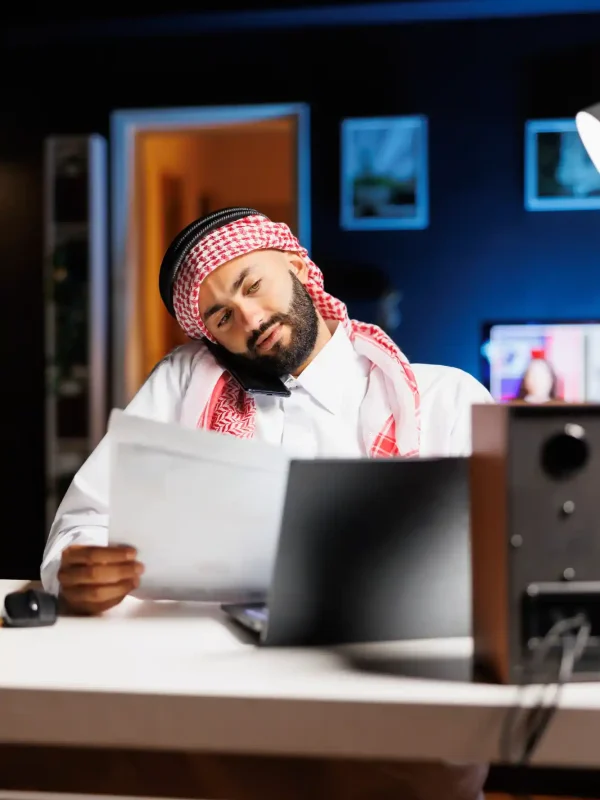detailed-shot-arab-man-using-laptop-mobile-device-communication-research-showcasing-proficiency-technology-muslim-guy-multitasking-talking-his-cellphone-comparing-notes